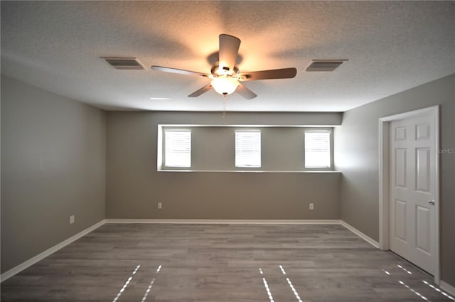 unfurnished room featuring dark hardwood / wood-style flooring, ceiling fan, and a textured ceiling