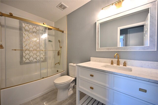 full bathroom featuring bath / shower combo with glass door, vanity, a textured ceiling, and toilet