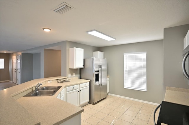 kitchen with white cabinets, sink, stainless steel fridge, and kitchen peninsula