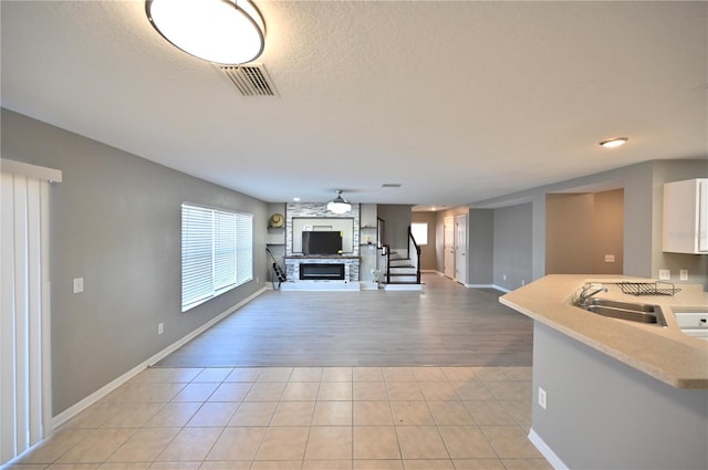 unfurnished living room with light tile patterned flooring, sink, and a textured ceiling