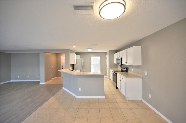 kitchen with white cabinetry, light tile patterned floors, stainless steel appliances, and a textured ceiling