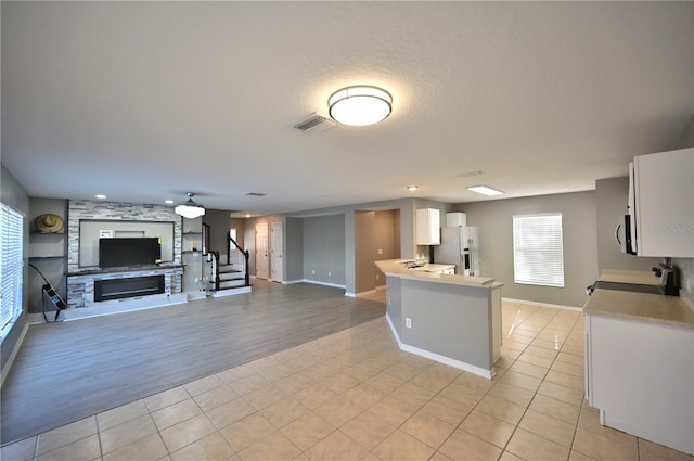 kitchen featuring appliances with stainless steel finishes, a large fireplace, light tile patterned floors, and white cabinets