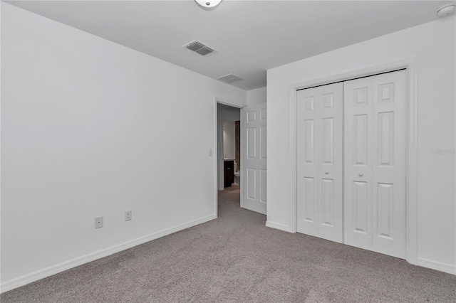 unfurnished bedroom featuring light colored carpet and a closet