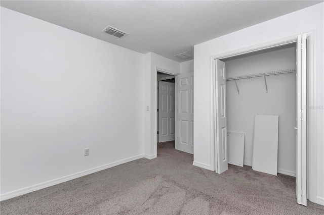 unfurnished bedroom with light colored carpet and a closet