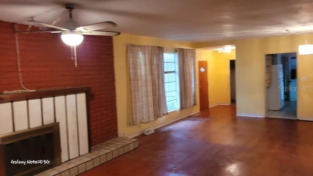 unfurnished living room featuring ceiling fan, a tiled fireplace, and hardwood / wood-style floors