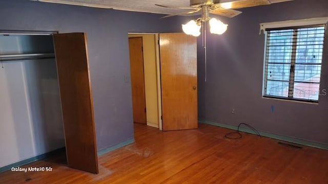 unfurnished bedroom with multiple windows, hardwood / wood-style floors, and ceiling fan