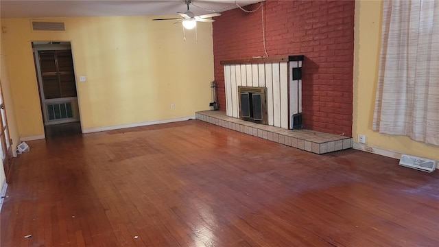 unfurnished living room with ceiling fan, wood-type flooring, and a brick fireplace