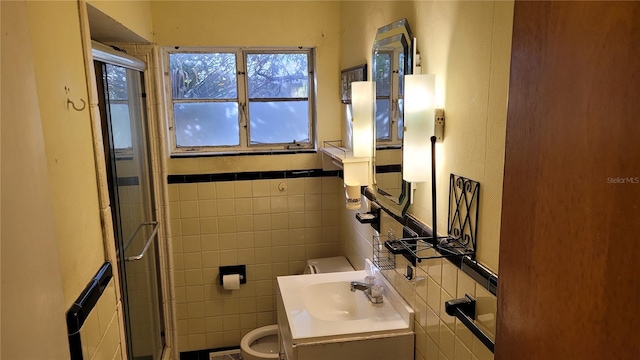 bathroom featuring tile walls, vanity, a shower with shower door, and toilet