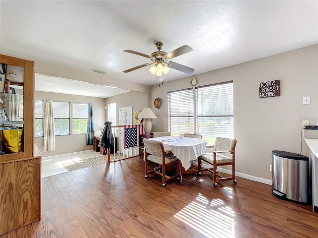 dining area featuring hardwood / wood-style flooring, ceiling fan, and a textured ceiling