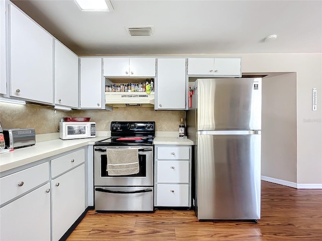 kitchen featuring hardwood / wood-style flooring, stainless steel appliances, decorative backsplash, and white cabinets