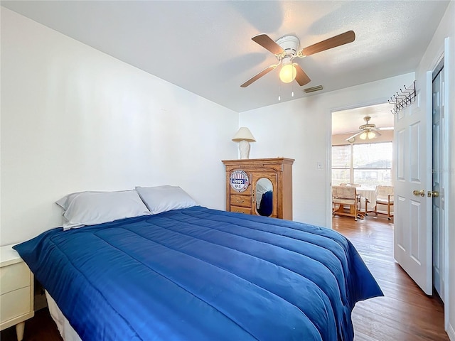 bedroom with a textured ceiling, wood-type flooring, and ceiling fan