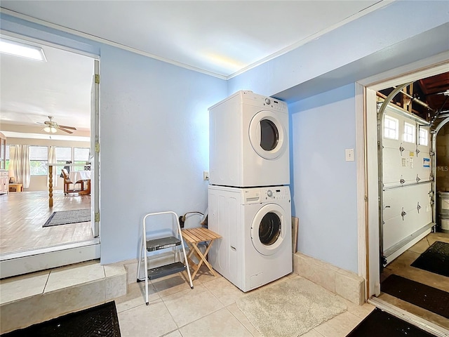 laundry area with ornamental molding, stacked washer / drying machine, light tile patterned floors, and ceiling fan