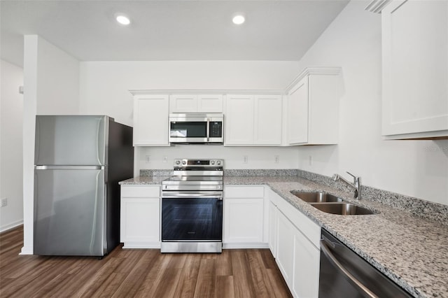 kitchen with appliances with stainless steel finishes, sink, white cabinets, dark hardwood / wood-style flooring, and light stone countertops