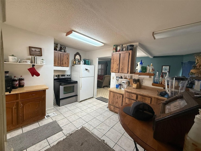 kitchen featuring white fridge, light tile patterned flooring, stainless steel range with electric cooktop, and a textured ceiling