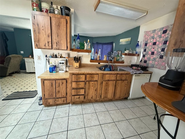 kitchen with sink, light tile patterned floors, and dishwasher