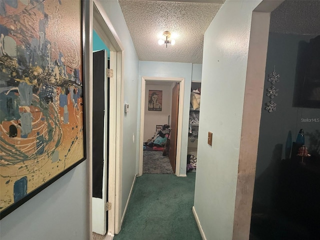 corridor featuring a textured ceiling and dark carpet