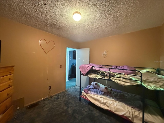 bedroom featuring a textured ceiling and dark colored carpet