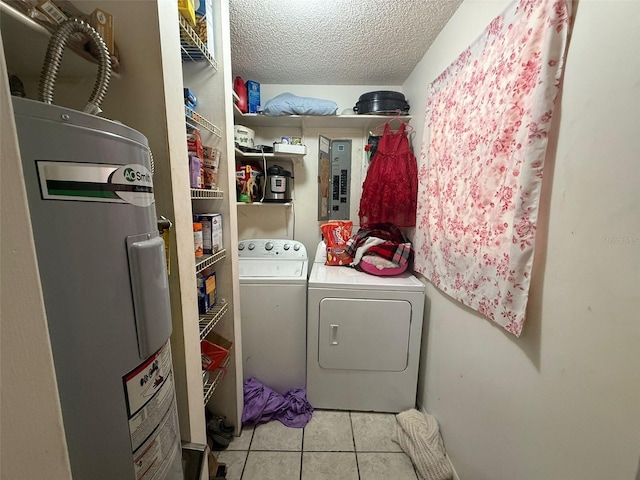 laundry area featuring electric water heater, light tile patterned floors, washer and dryer, and a textured ceiling