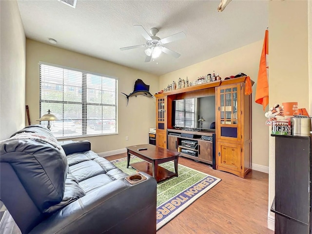 living room featuring a textured ceiling, ceiling fan, and light hardwood / wood-style floors