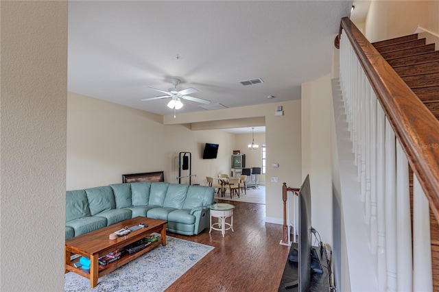 living room with dark hardwood / wood-style flooring and ceiling fan with notable chandelier