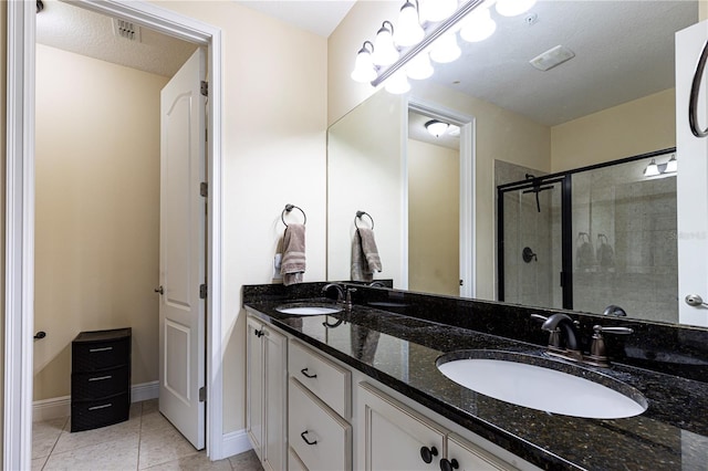 bathroom featuring tile patterned floors, a shower with door, vanity, and a textured ceiling