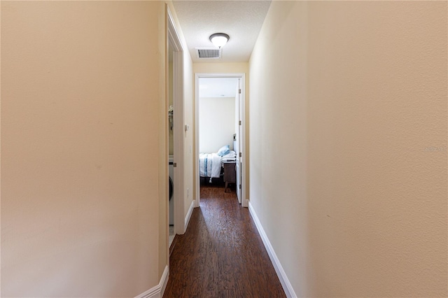 hallway with dark wood-type flooring and a textured ceiling