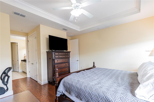 bedroom featuring hardwood / wood-style flooring, ornamental molding, a raised ceiling, and ceiling fan