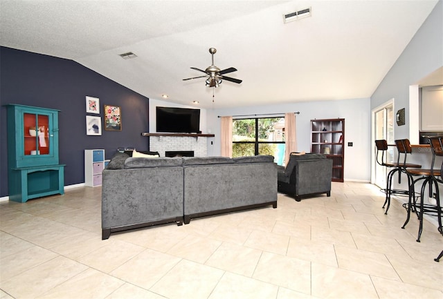 living room featuring light tile patterned flooring, ceiling fan, vaulted ceiling, and a brick fireplace