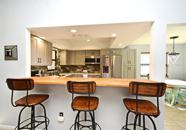 kitchen with backsplash, a wealth of natural light, stainless steel appliances, and a kitchen bar