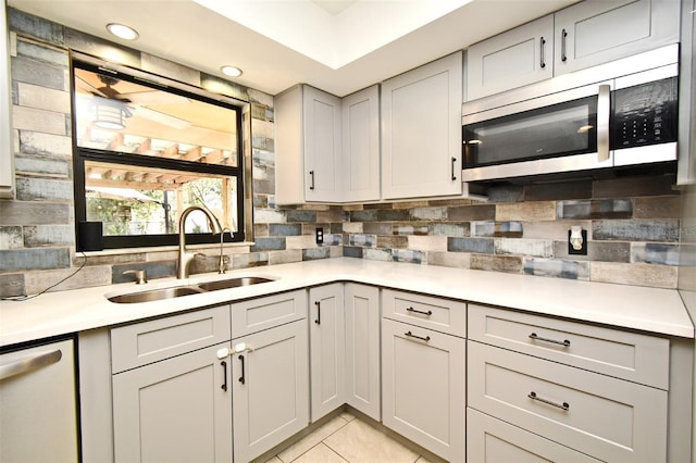 kitchen featuring dishwasher, sink, decorative backsplash, and light tile patterned floors