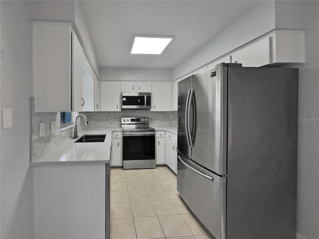 kitchen with sink, light tile patterned floors, appliances with stainless steel finishes, white cabinetry, and backsplash