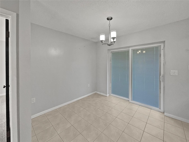 empty room featuring a textured ceiling and a chandelier