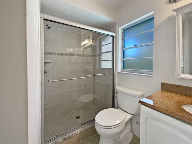 bathroom featuring a shower with door, vanity, and toilet