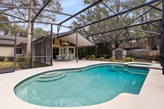 view of swimming pool with an in ground hot tub, glass enclosure, a shed, and a patio area