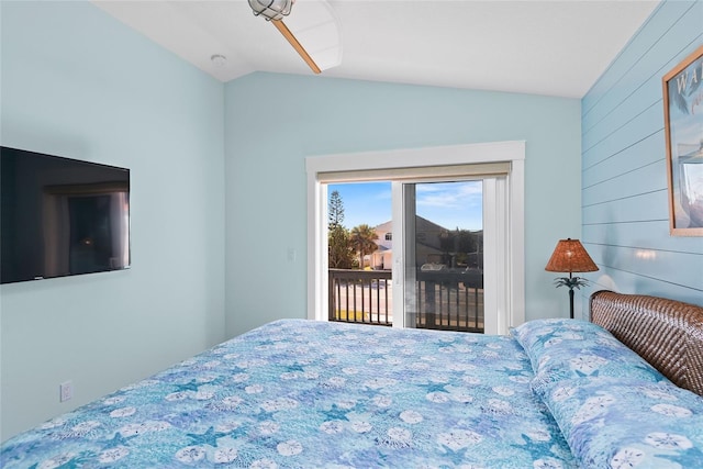 bedroom with access to exterior, vaulted ceiling, and wood walls