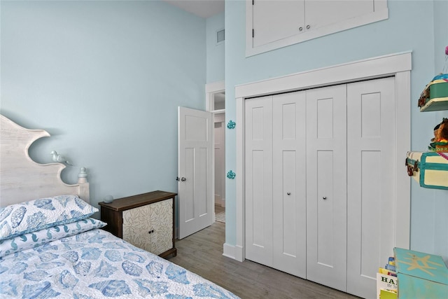 bedroom featuring a closet, dark hardwood / wood-style floors, and a high ceiling