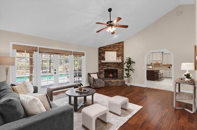 living room featuring dark wood-type flooring, ceiling fan, plenty of natural light, and a fireplace