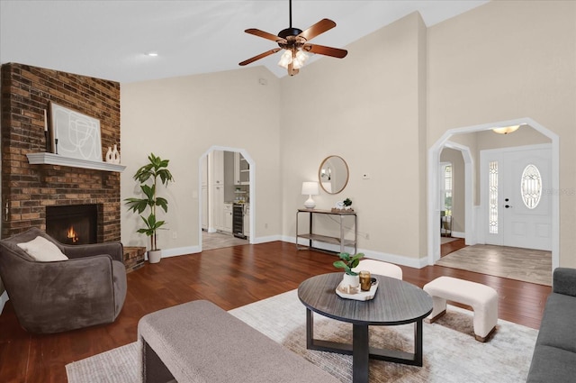 living room with hardwood / wood-style flooring, a fireplace, high vaulted ceiling, and ceiling fan