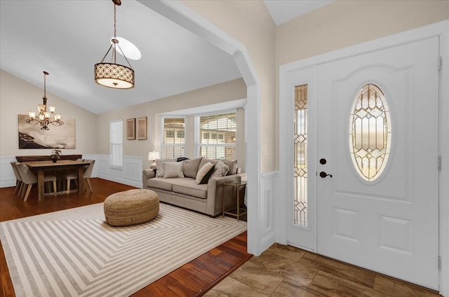 entrance foyer featuring wood-type flooring, lofted ceiling, and a notable chandelier