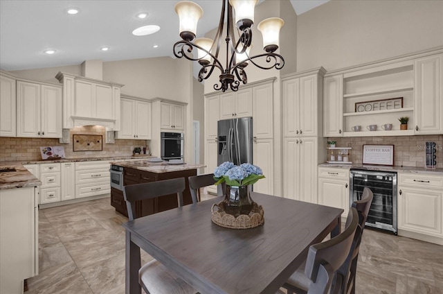 kitchen featuring pendant lighting, a center island, light stone countertops, white cabinets, and beverage cooler