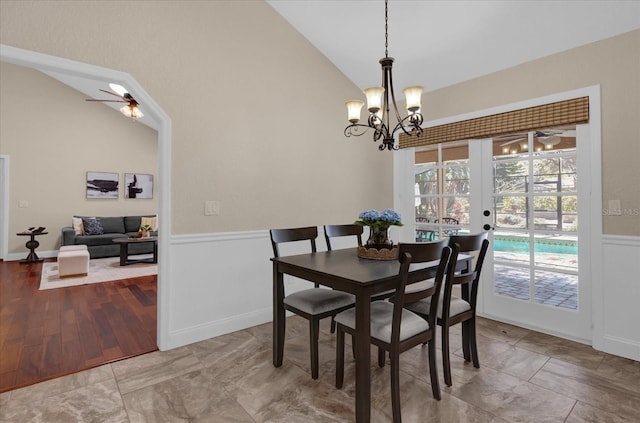 dining room with hardwood / wood-style flooring, ceiling fan with notable chandelier, high vaulted ceiling, and french doors