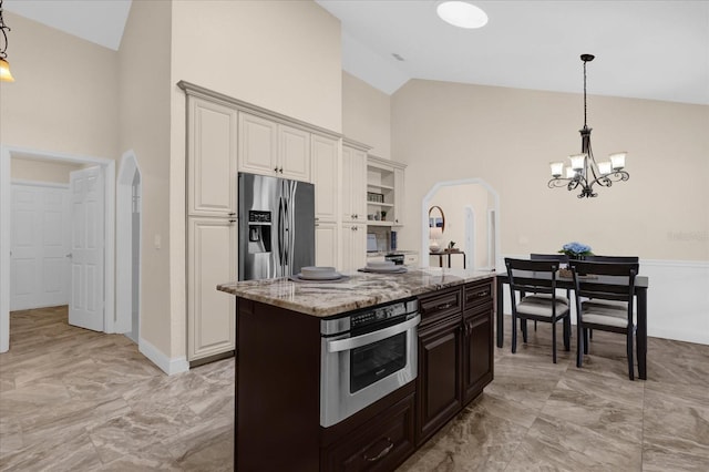 kitchen with decorative light fixtures, a kitchen island, light stone countertops, and appliances with stainless steel finishes