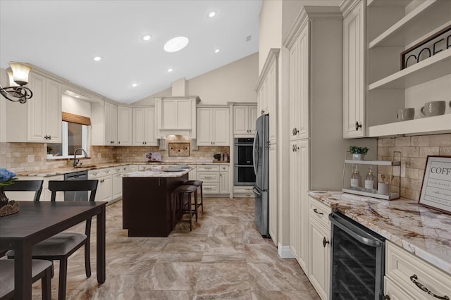 kitchen with a kitchen island, appliances with stainless steel finishes, a breakfast bar area, beverage cooler, and light stone counters