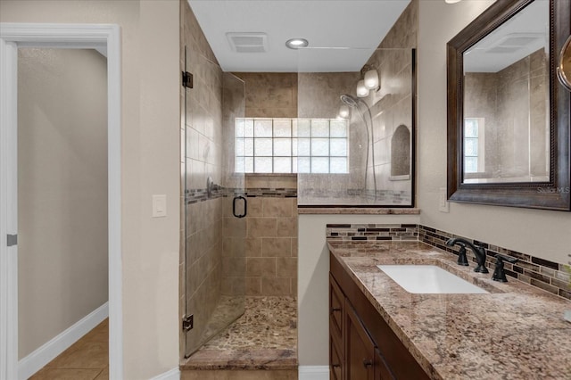 bathroom featuring vanity, a shower with shower door, tile patterned flooring, and backsplash