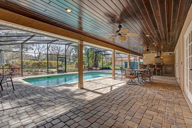 view of pool with ceiling fan, an outdoor kitchen, a lanai, and a patio