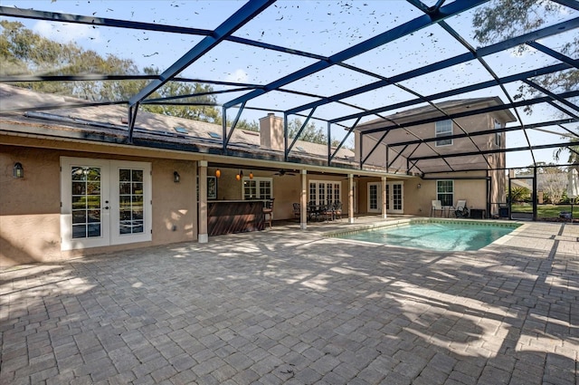 view of pool with a patio, an outdoor bar, ceiling fan, glass enclosure, and french doors