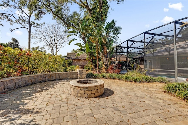 view of patio featuring glass enclosure and a fire pit