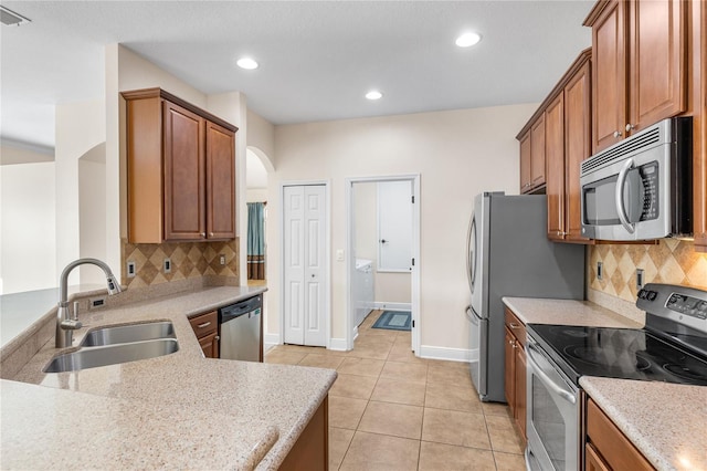 kitchen featuring light tile patterned flooring, appliances with stainless steel finishes, sink, and decorative backsplash