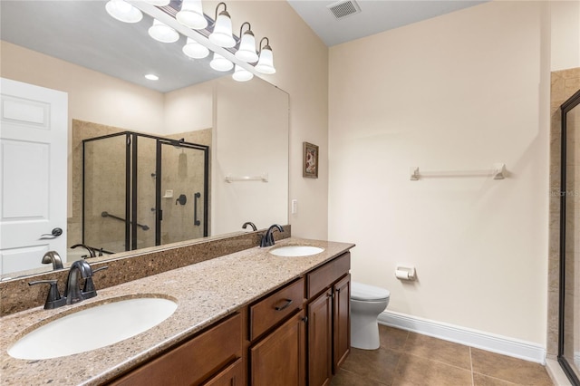 bathroom featuring tile patterned flooring, vanity, a shower with shower door, and toilet