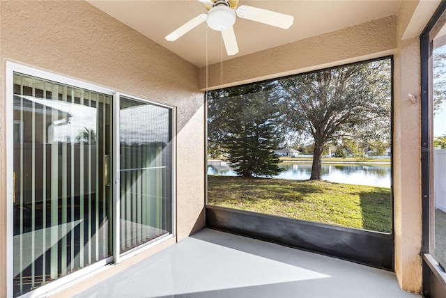 unfurnished sunroom with a water view and ceiling fan